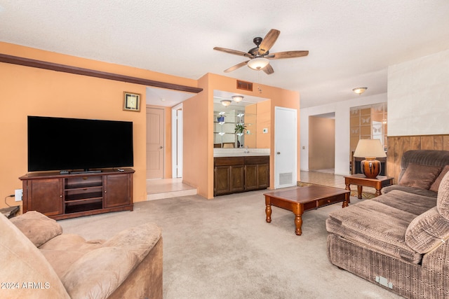 living room with ceiling fan, carpet floors, a textured ceiling, and wooden walls