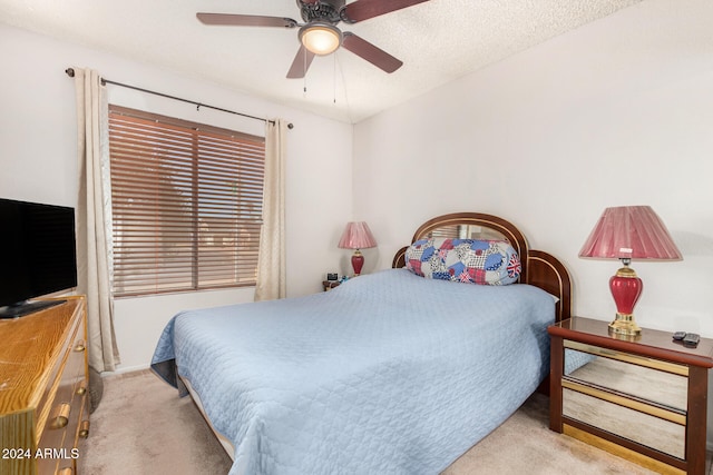 bedroom with ceiling fan, light colored carpet, and a textured ceiling