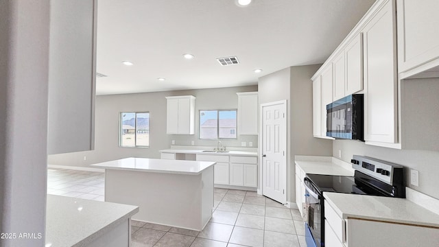 kitchen featuring stainless steel electric range oven, black microwave, a sink, a center island, and light tile patterned flooring