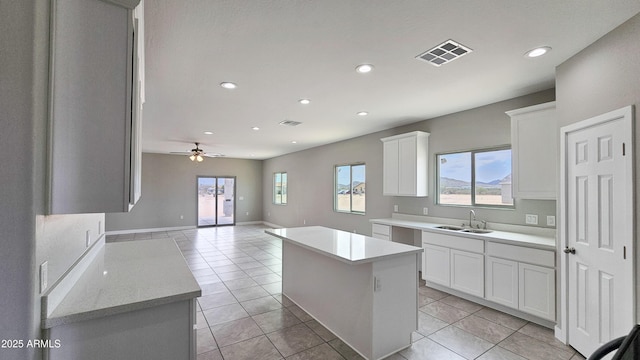 kitchen featuring a sink, a center island, white cabinets, light countertops, and recessed lighting