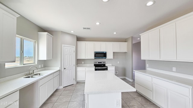 kitchen with appliances with stainless steel finishes, a sink, a center island, recessed lighting, and light tile patterned floors