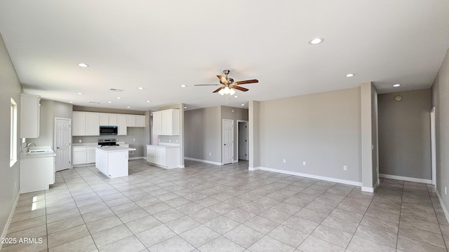 unfurnished living room featuring ceiling fan, light tile patterned flooring, recessed lighting, a sink, and baseboards