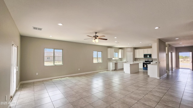unfurnished living room featuring healthy amount of natural light, ceiling fan, light tile patterned floors, recessed lighting, and baseboards
