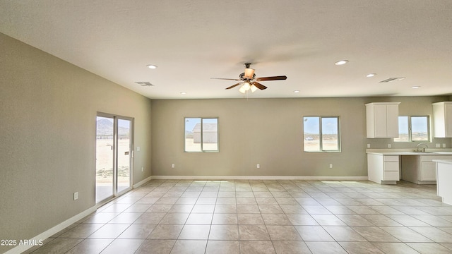 empty room with a sink, ceiling fan, recessed lighting, light tile patterned floors, and baseboards
