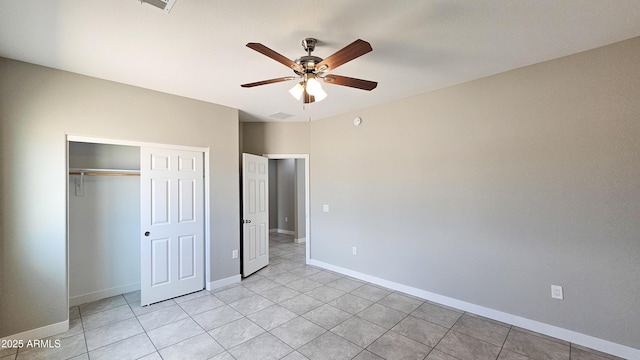 unfurnished bedroom with a closet, baseboards, light tile patterned floors, and a ceiling fan