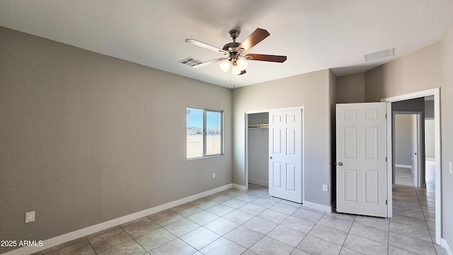 unfurnished bedroom with light tile patterned floors, a closet, baseboards, and a ceiling fan