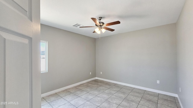 spare room with a ceiling fan, light tile patterned floors, and baseboards