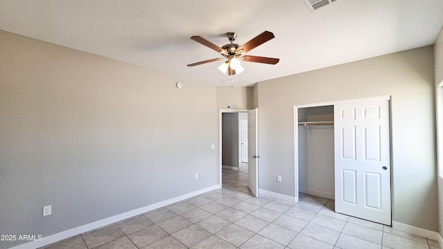 unfurnished bedroom with a closet, light tile patterned floors, baseboards, and a ceiling fan