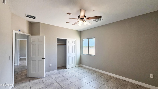 unfurnished bedroom featuring light tile patterned floors, a closet, baseboards, and ceiling fan