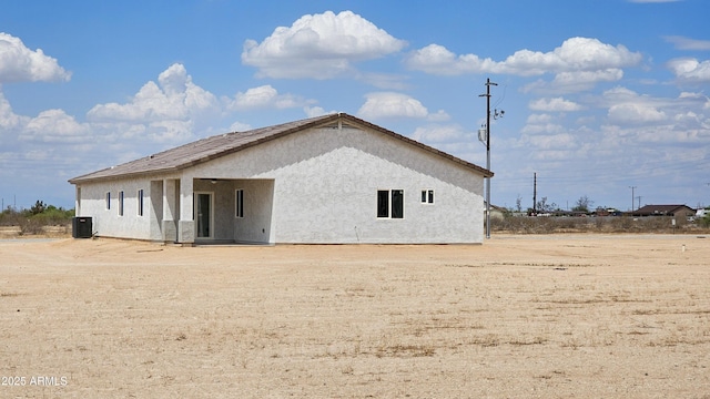 back of property with cooling unit and stucco siding