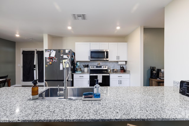 1635 W Cottonwood Bluffs Dr, Benson, AZ 85602 - kitchen with appliances with stainless steel finishes, white cabinets, light stone countertops, backsplash, and recessed lighting