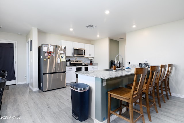 1635 W Cottonwood Bluffs Dr, Benson, AZ 85602 - kitchen with stainless steel appliances, light wood finished floors, a breakfast bar, white cabinets, and recessed lighting