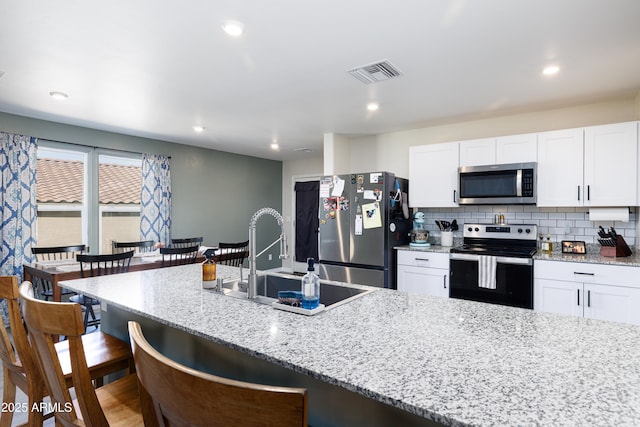 1635 W Cottonwood Bluffs Dr, Benson, AZ 85602 - kitchen featuring stainless steel appliances, a sink, a breakfast bar, white cabinets, and light stone countertops
