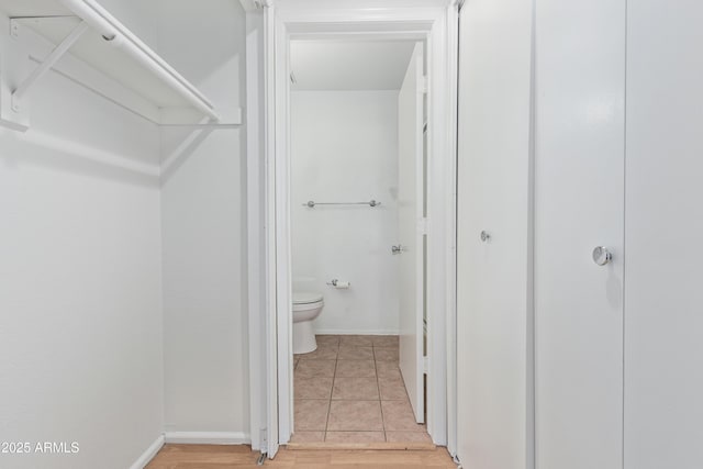 interior space featuring tile patterned flooring, baseboards, and toilet