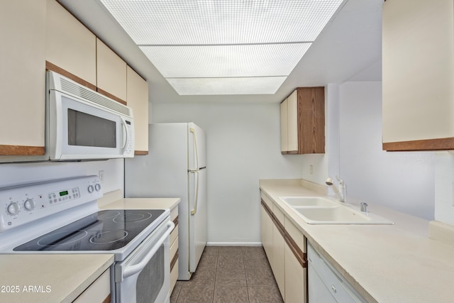 kitchen with light countertops, light tile patterned flooring, a sink, white appliances, and baseboards