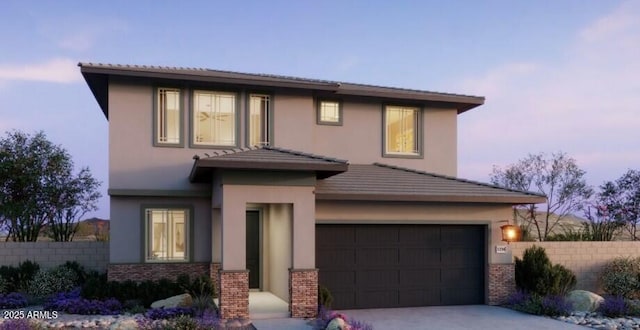 view of front facade with driveway, fence, a garage, stucco siding, and brick siding