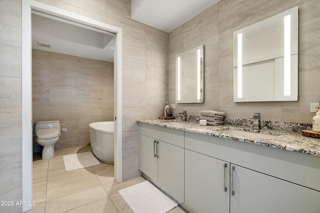 7180 E Kierland Blvd Unit 814, Scottsdale, AZ 85254 - bathroom featuring tile walls, double vanity, a freestanding bath, tile patterned floors, and toilet