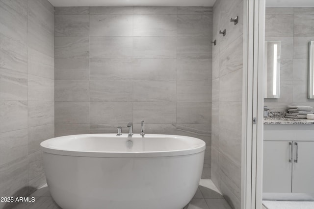 7180 E Kierland Blvd Unit 814, Scottsdale, AZ 85254 - bathroom featuring a soaking tub, tile walls, vanity, and tile patterned floors