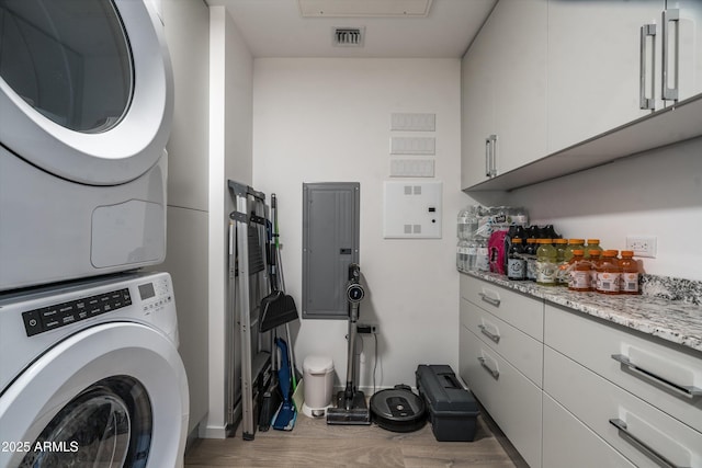 7180 E Kierland Blvd Unit 814, Scottsdale, AZ 85254 - laundry area featuring stacked washing machine and dryer, electric panel, baseboards, and wood finished floors