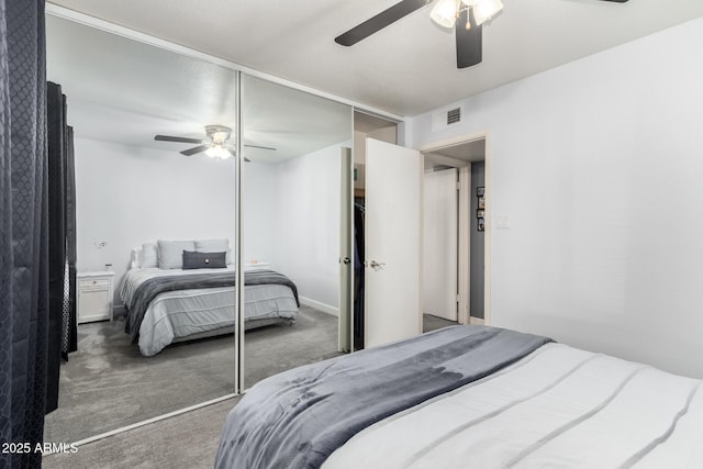 bedroom with a closet, dark carpet, visible vents, and a ceiling fan