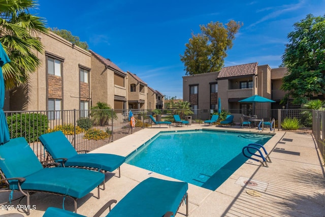 pool with a patio area, fence, and a residential view