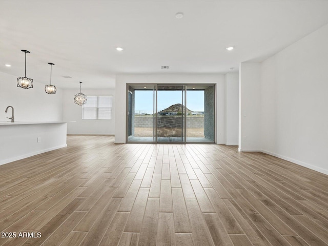 unfurnished living room featuring healthy amount of natural light, light wood-type flooring, baseboards, and recessed lighting