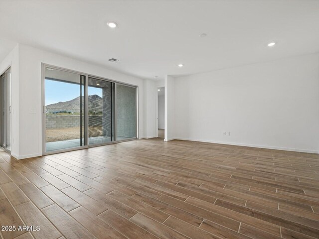 spare room featuring wood finished floors, recessed lighting, and baseboards