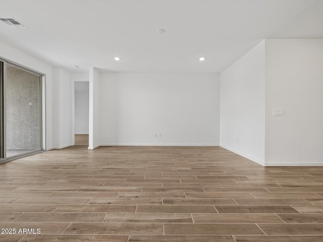 empty room with wood finished floors, recessed lighting, and baseboards