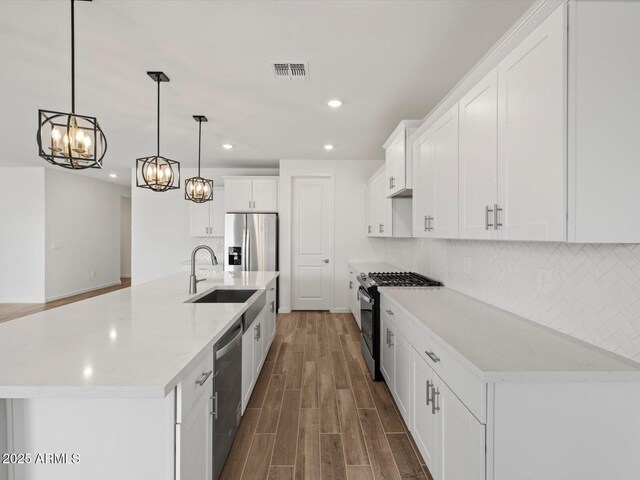kitchen with stainless steel appliances, a chandelier, a sink, recessed lighting, and wood finished floors