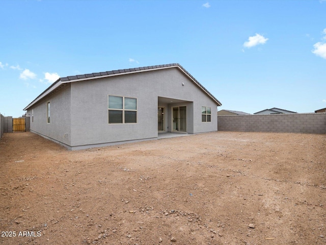 rear view of house featuring a fenced backyard and stucco siding