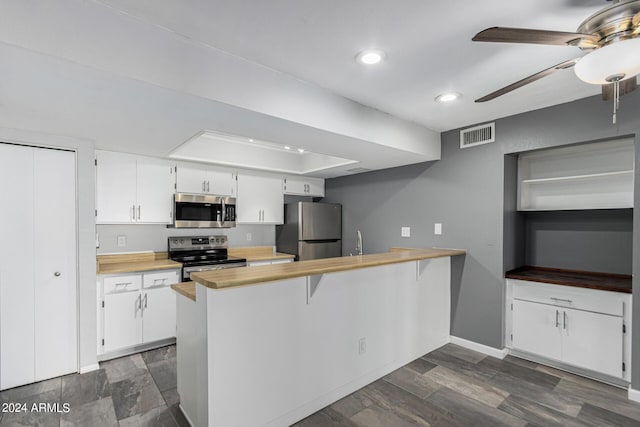 kitchen with kitchen peninsula, a kitchen bar, stainless steel appliances, and white cabinetry