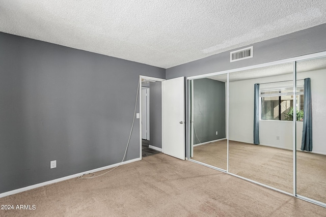 unfurnished bedroom featuring a closet, light colored carpet, and a textured ceiling