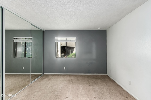 unfurnished bedroom with carpet flooring, a textured ceiling, and a closet