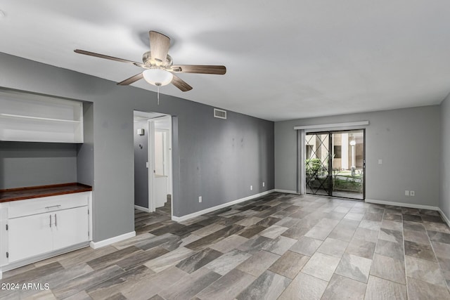 unfurnished living room with ceiling fan and built in features