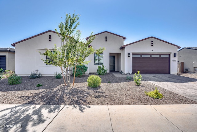 view of front of home with decorative driveway, an attached garage, and stucco siding