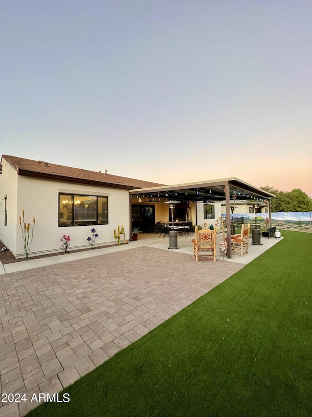 rear view of house with a patio, a yard, an outdoor living space, and stucco siding