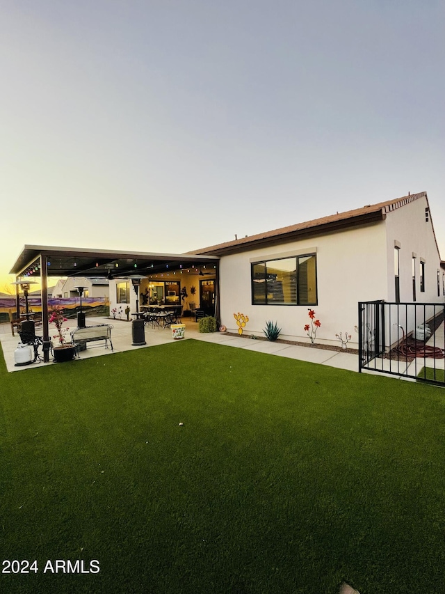 back of house featuring a lawn, a patio area, and stucco siding