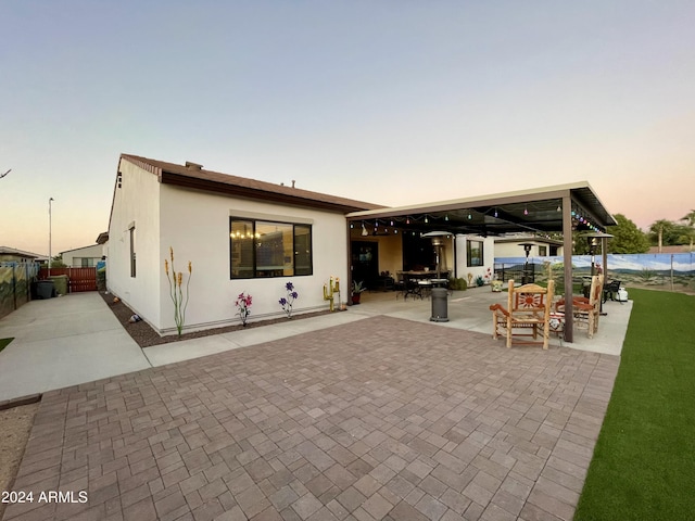 rear view of house with a patio area, fence, and stucco siding