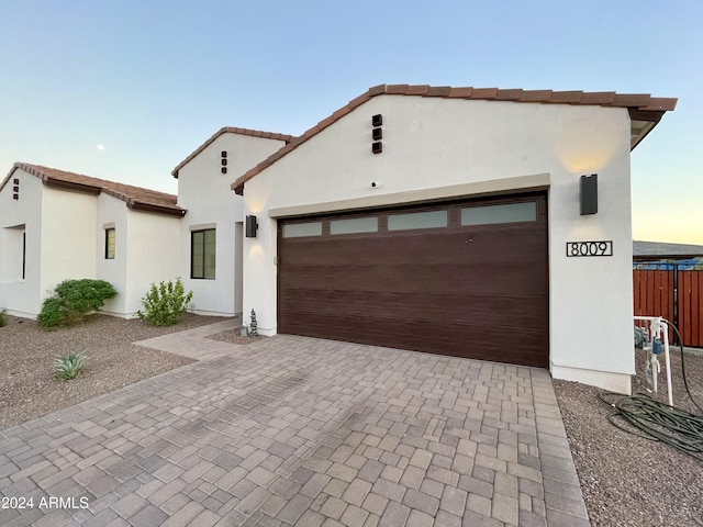 view of front facade featuring a garage, decorative driveway, and stucco siding