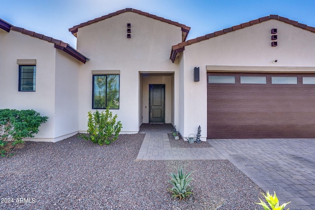 mediterranean / spanish home featuring decorative driveway, an attached garage, and stucco siding