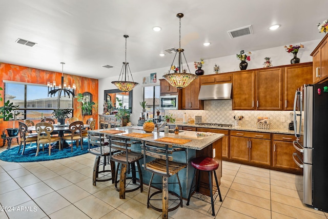 kitchen featuring light tile patterned floors, stainless steel appliances, visible vents, and under cabinet range hood