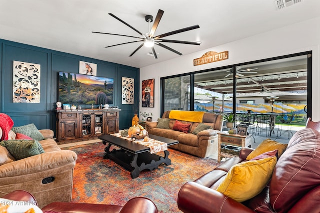 living room featuring a ceiling fan, visible vents, and a decorative wall