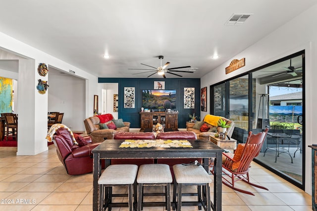 living area featuring light tile patterned floors, baseboards, visible vents, and a ceiling fan