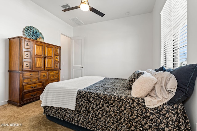 bedroom featuring a ceiling fan, visible vents, and light carpet