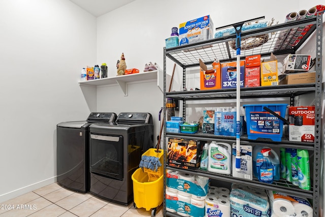 clothes washing area featuring laundry area, tile patterned flooring, baseboards, and washing machine and clothes dryer