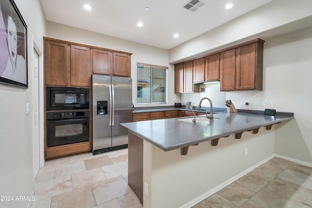 kitchen featuring black appliances, a kitchen breakfast bar, kitchen peninsula, and sink