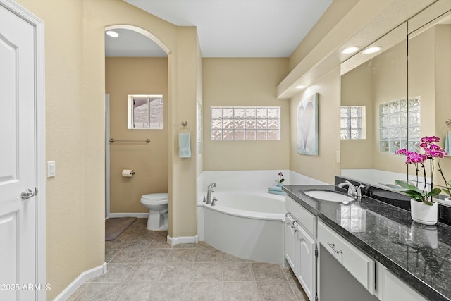 bathroom featuring tile patterned flooring, vanity, a tub to relax in, and toilet