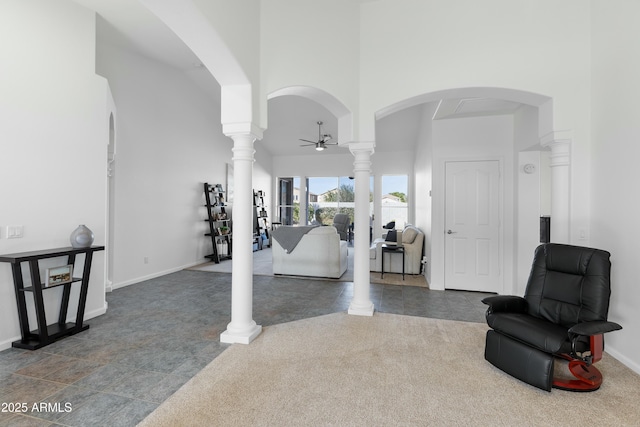 interior space with ceiling fan, decorative columns, and a towering ceiling