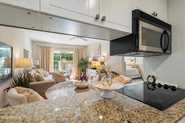 kitchen with open floor plan, tile countertops, white cabinetry, and ceiling fan