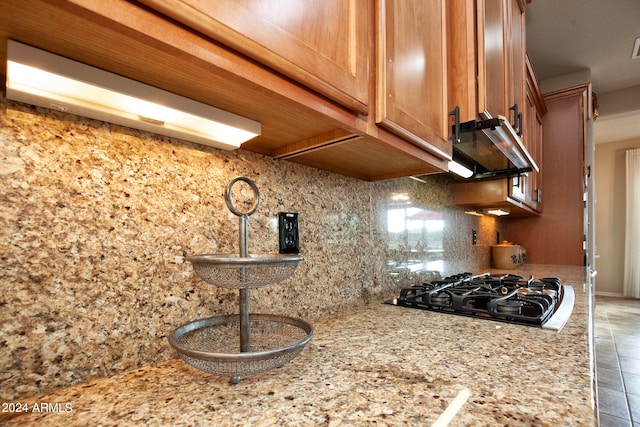 kitchen with gas cooktop, light stone counters, tile patterned flooring, and tasteful backsplash